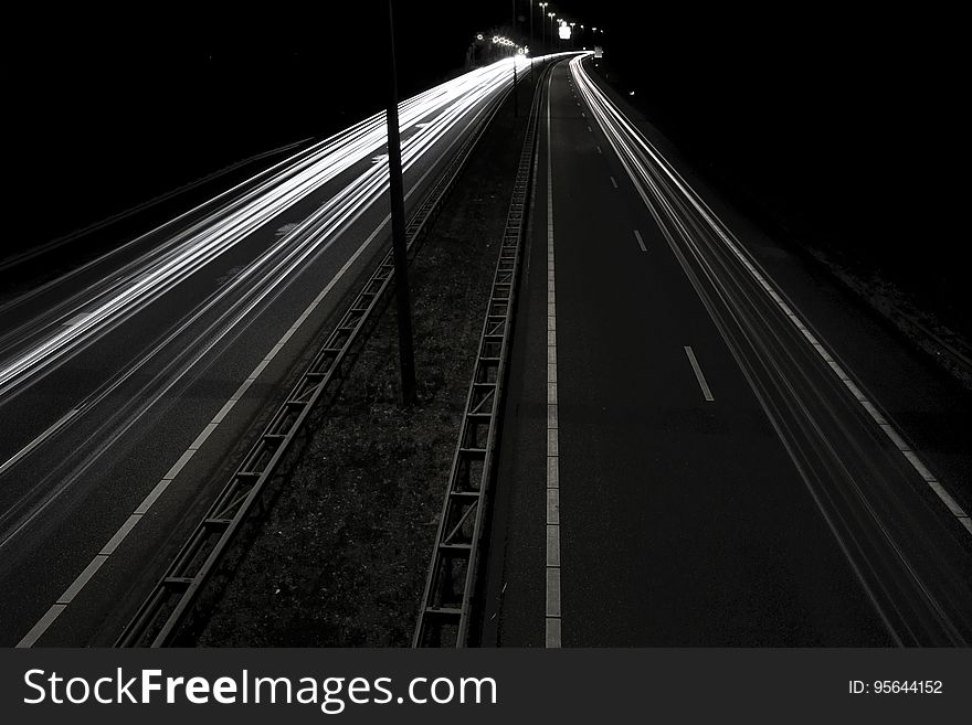 White streaks from blur of headlights on dark roadway at night in black and white. White streaks from blur of headlights on dark roadway at night in black and white.