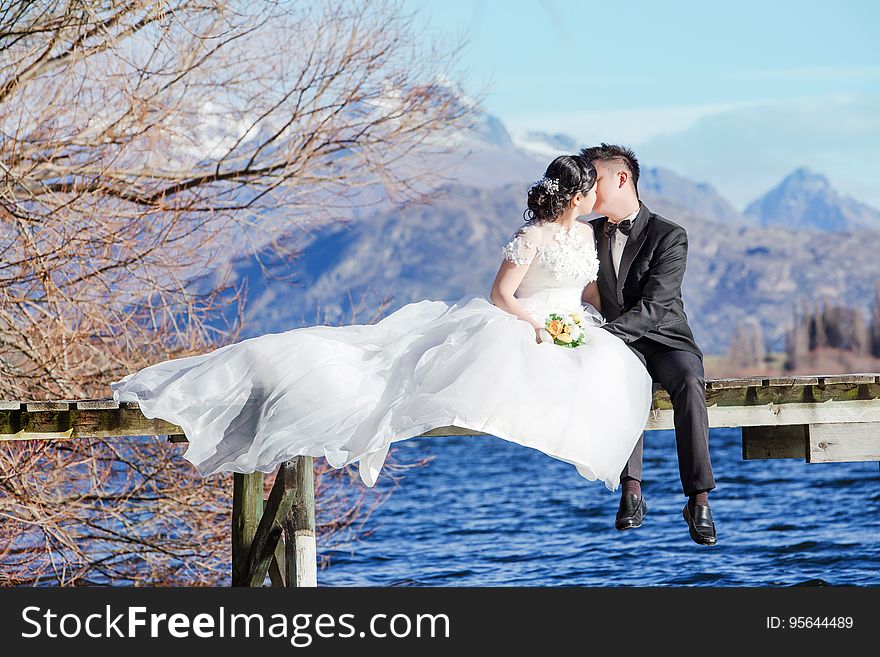 Newlywed couple kissing on a pier by the water. Newlywed couple kissing on a pier by the water.