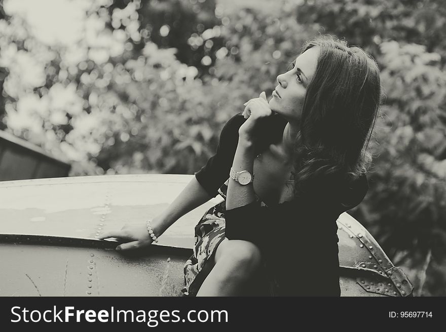 Black and white view of thoughtful woman sat outdoors looking to side,