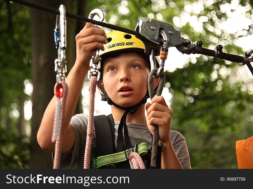 A boy fixing a cable on a zipline. A boy fixing a cable on a zipline.