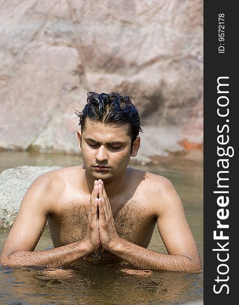 Man having yoga in water between stones