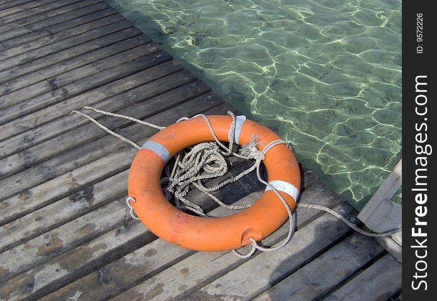 Orange colored resque ring on a pier in the sea