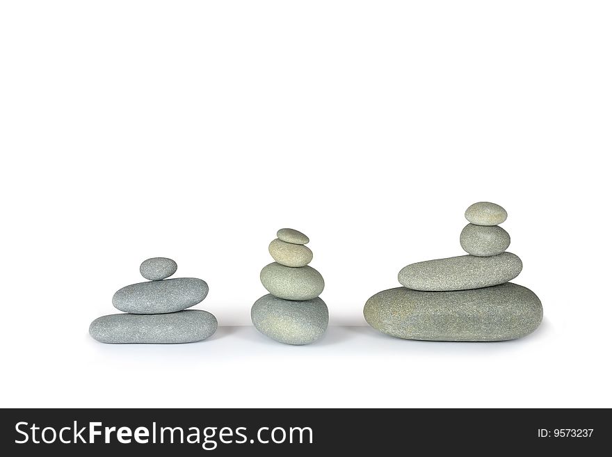 Three stacks of balanced grey stone pebbles, over white background.