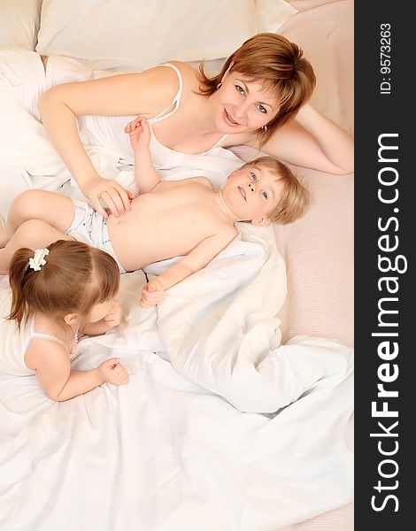 Portrait of a happy mother with her daughter and son  in a bedroom. Portrait of a happy mother with her daughter and son  in a bedroom.