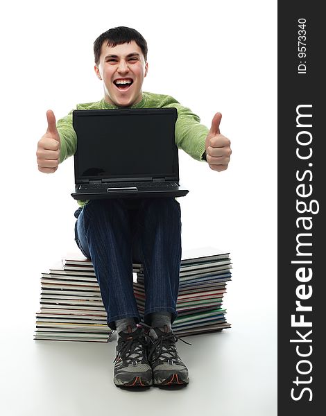 Portrait of a young man sitting on books with a laptop. Theme: education career, success. Portrait of a young man sitting on books with a laptop. Theme: education career, success.