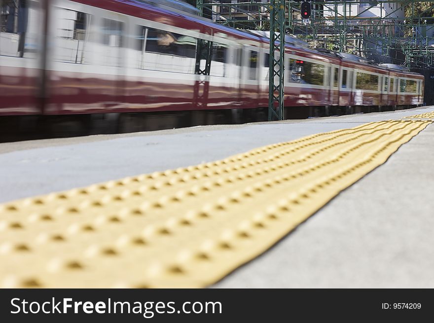 A red moving train at a train station from ground level.