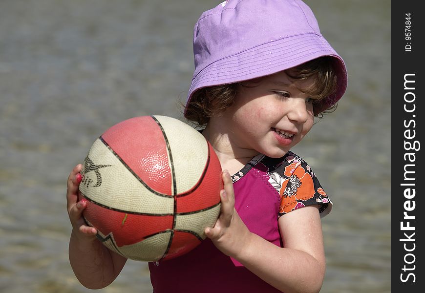 This little girl was playing with a ball at a paddling pool. This little girl was playing with a ball at a paddling pool.