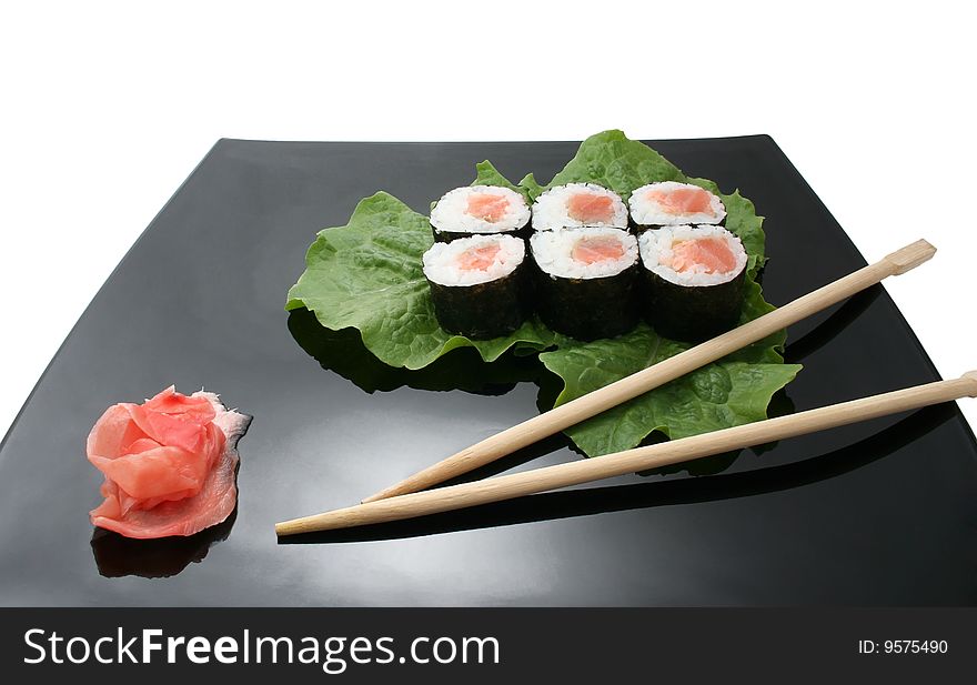 A sushi roll with ginger and stick on Japanese plate. A sushi roll with ginger and stick on Japanese plate