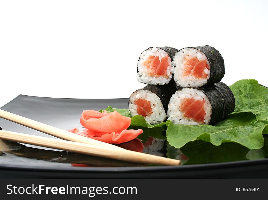 A sushi roll with ginger and stick on Japanese plate. A sushi roll with ginger and stick on Japanese plate