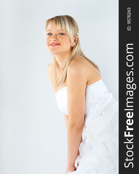 Young bride in white dress on gray background