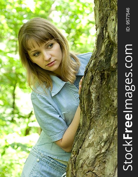 The beautiful girl in park to stand near an old tree. The beautiful girl in park to stand near an old tree