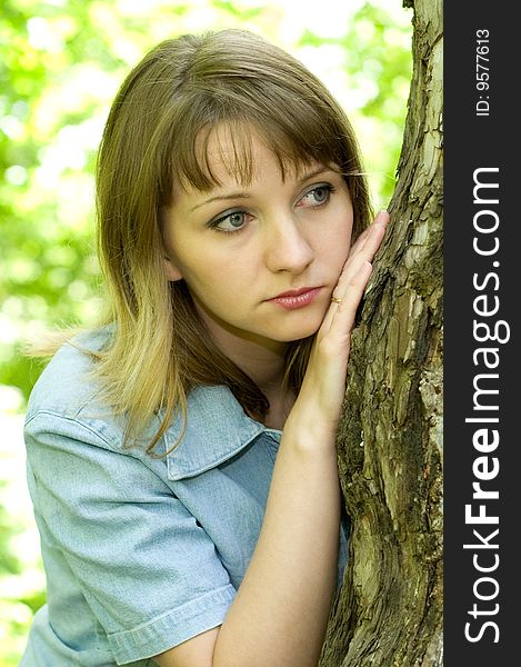 The beautiful girl in park to stand near an old tree. The beautiful girl in park to stand near an old tree