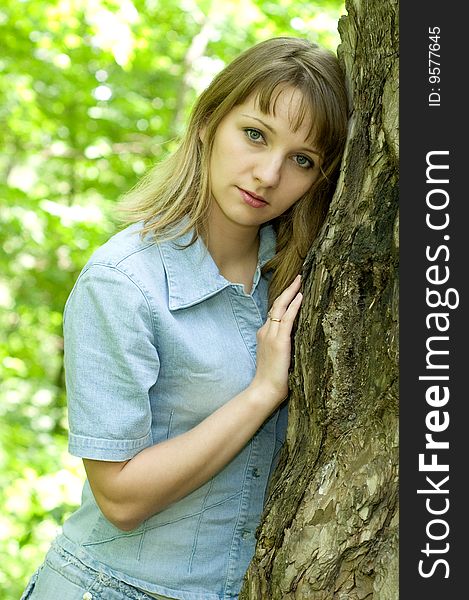 The beautiful girl in park to stand near an old tree. The beautiful girl in park to stand near an old tree