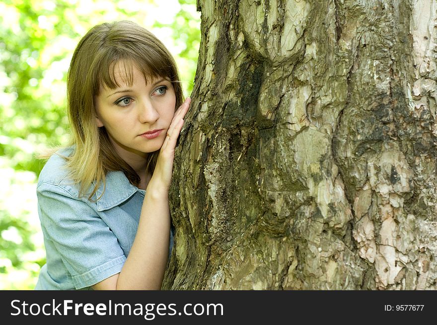 The beautiful girl in park to stand near an old tree. The beautiful girl in park to stand near an old tree