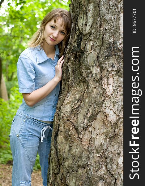 The beautiful girl in park to stand near an old tree. The beautiful girl in park to stand near an old tree