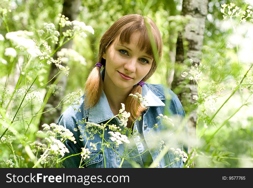 The beautiful girl in park sits on a green grass