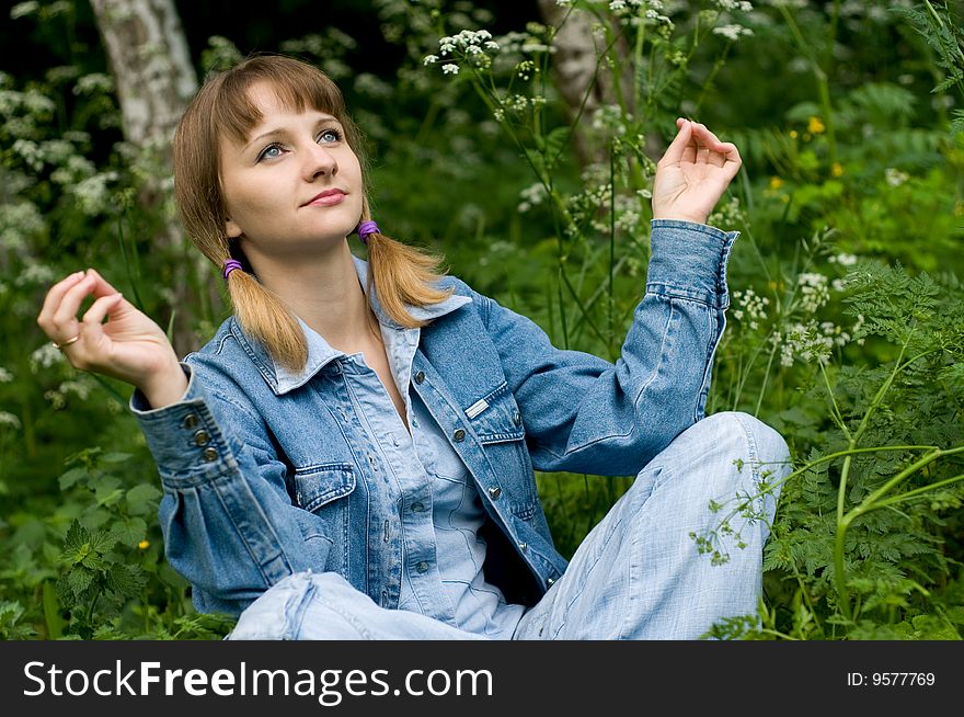 The beautiful girl in park sits on a green grass