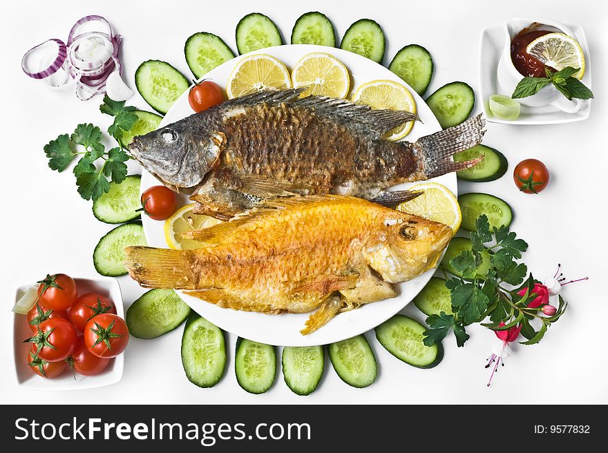 Beautiful dinner with fried fishes and tomatoes and cucumbers. Beautiful dinner with fried fishes and tomatoes and cucumbers