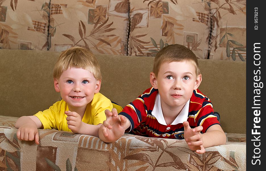 Portrait of two boys laying on a sofa of the house