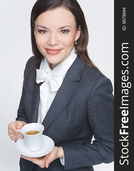 The woman in a business suit holds a cup with tea