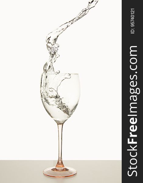Crystal wine glass with white wine splashing into goblet. Crystal wine glass with white wine splashing into goblet.