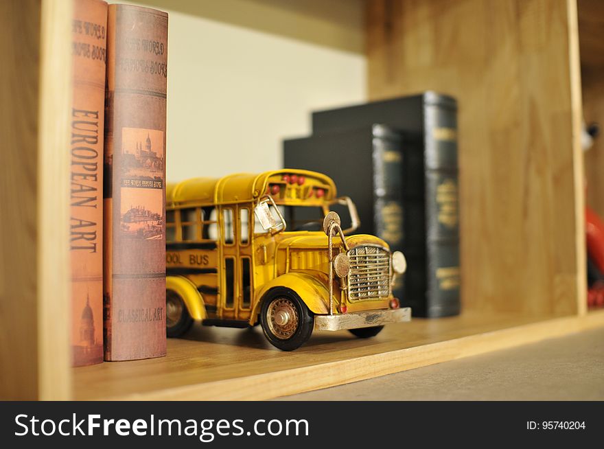 A yellow toy school bus in a bookshelf. A yellow toy school bus in a bookshelf.