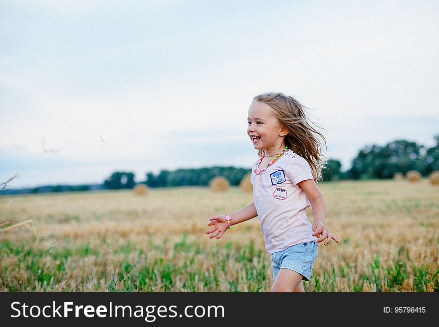 Carefree happy young blond girl running in stubble field after the harvest. Carefree happy young blond girl running in stubble field after the harvest.