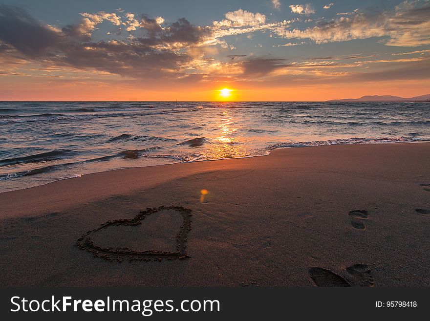 A heart drawn in the sand on the beach at sunset. A heart drawn in the sand on the beach at sunset.