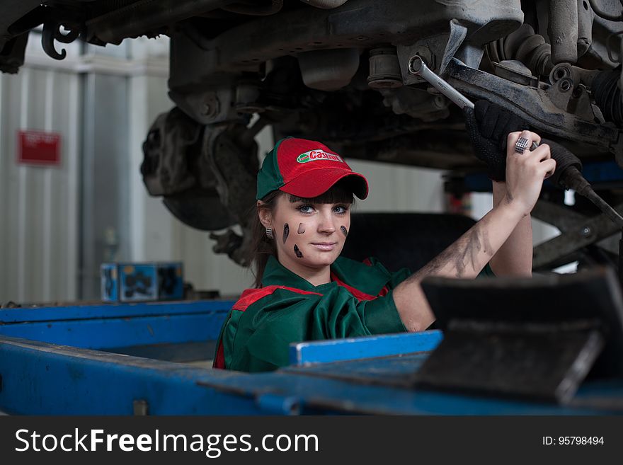 Female automotive mechanic working on car in garage.
