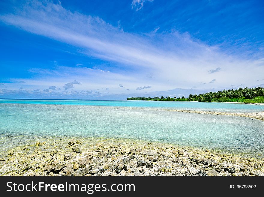 Sandy beach along coastline of blue waters with blue skies on sunny day. Sandy beach along coastline of blue waters with blue skies on sunny day.