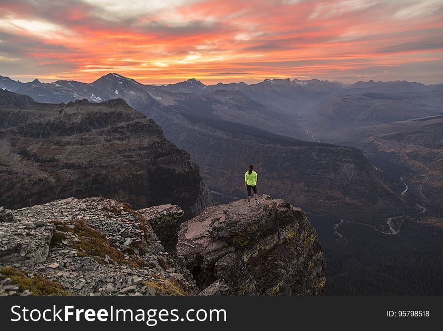 A hiker standing on a rock on a mountain top. A hiker standing on a rock on a mountain top.