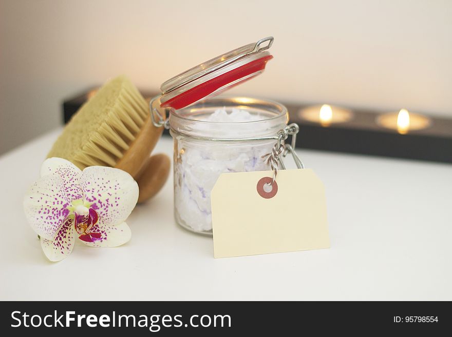 A jar of bath salt with a brush and orchid flower. A jar of bath salt with a brush and orchid flower.