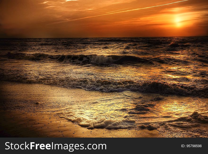 A beautiful coastal sunset with waves crashing on the shore.