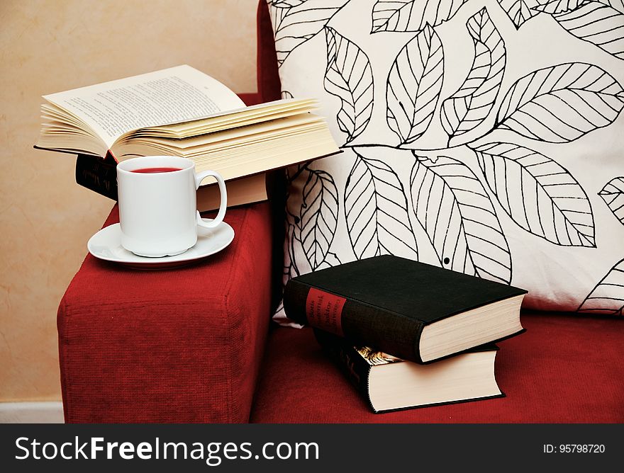 Closed and open books on armchair with cup of coffee. Closed and open books on armchair with cup of coffee.