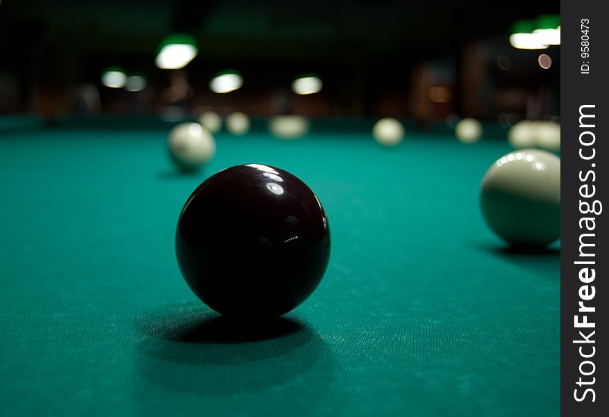 Black ball for playing billiards on green table. Black ball for playing billiards on green table