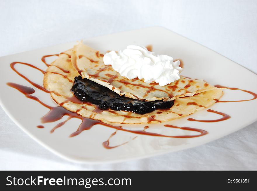 Pancake with blueberries jam, whipped cream and chocolate