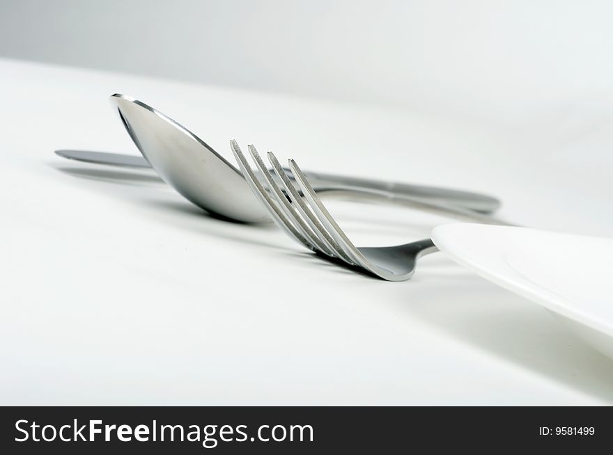 Fork, spoon and knife with white plate