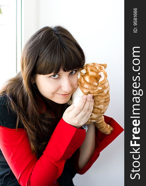 A girl holds a red toy-kitten. A girl holds a red toy-kitten