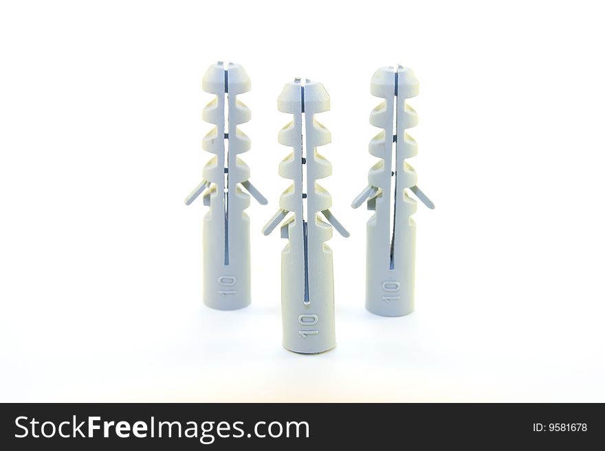 Three grey plastic wall plugs in a triangle on a white background. Three grey plastic wall plugs in a triangle on a white background