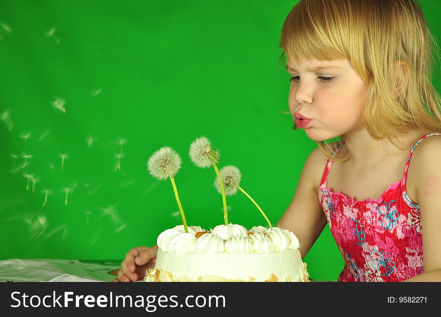 The girl blows on a pie, on which instead of candles - dandelions. The girl blows on a pie, on which instead of candles - dandelions