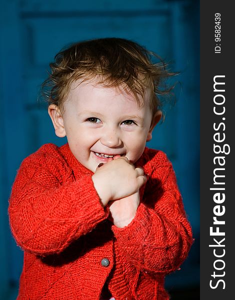 A smiling little boy  with dishevelled blond  hair on the blue background. A smiling little boy  with dishevelled blond  hair on the blue background