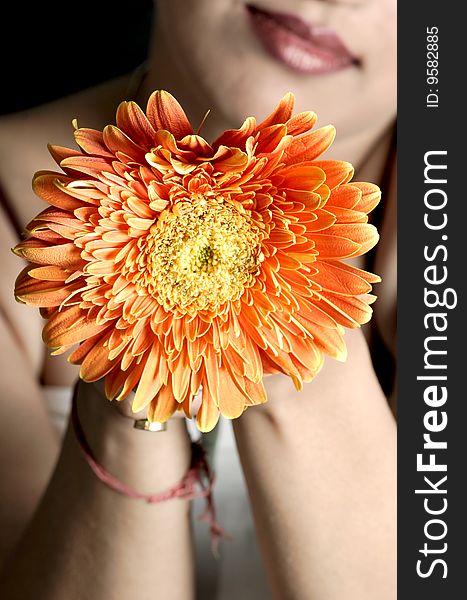 Model posing with flower in hands.