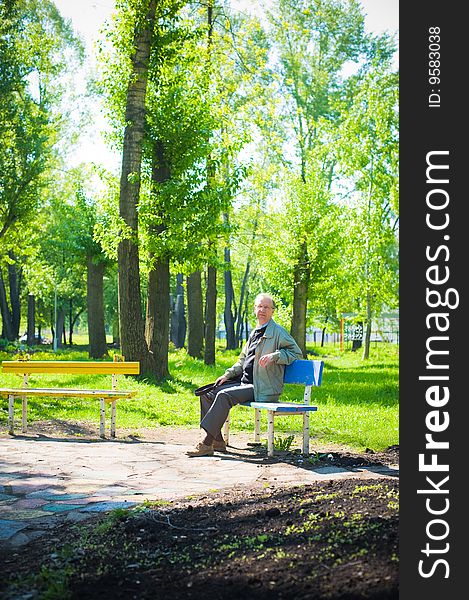 Mature man sits on a bench in park