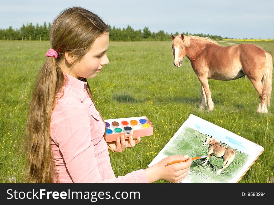 The girl draws paints a horse on a meadow. The girl draws paints a horse on a meadow.