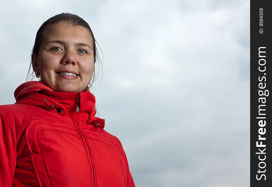 Portrait of a girl in red coat on gray sky background