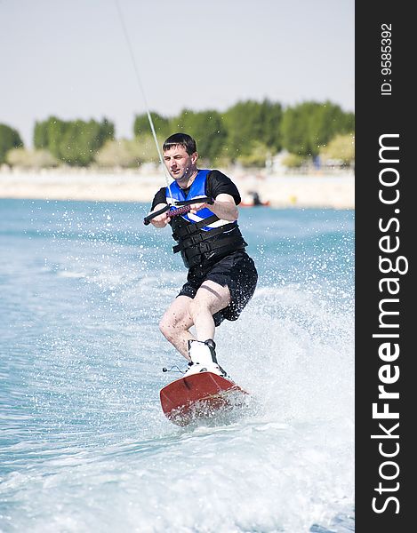 A wakeboarder enjoying the action of riding the wake of the boat. A wakeboarder enjoying the action of riding the wake of the boat.