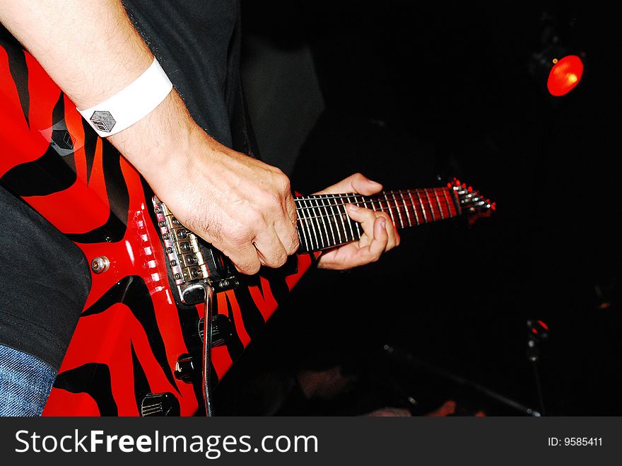Guitarist with red electric guitar on stage performing. Guitarist with red electric guitar on stage performing