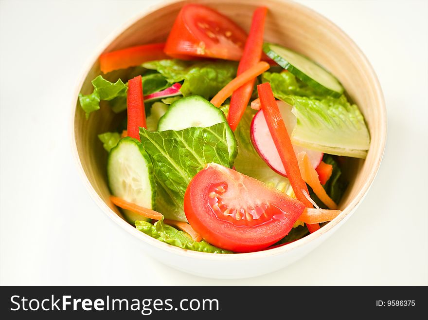 Green salad in bamboo bowl with delicious vegetables.