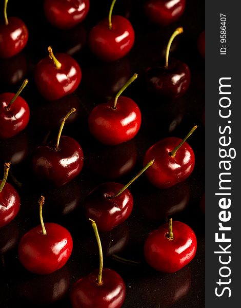 Rows of cherries on shiny black glass. Rows of cherries on shiny black glass