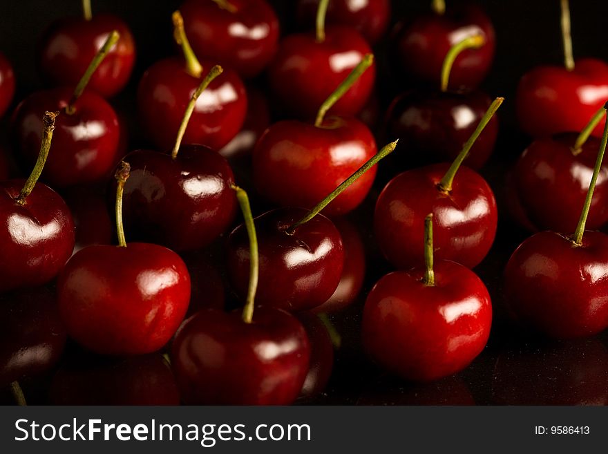 Rows of cherries on shiny black glass. Rows of cherries on shiny black glass